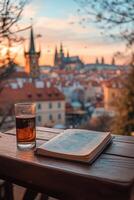 A cozy evening with a book and drink overlooking Pragues historic skyline at sunset photo
