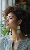 Elegant woman showcasing jewelry while enjoying a sunny day indoors near greenery photo