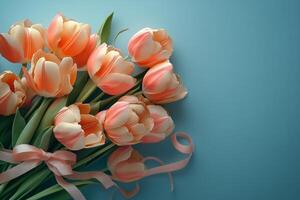 Fresh pink tulips arranged in a bouquet on a blue background with a delicate ribbon photo
