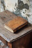 An old leather bound book resting on a rustic wooden table in a weathered space photo