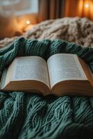 A cozy reading experience with an open book on a knit blanket near warm lights in the evening photo