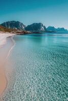 A tranquil beach with clear water and mountains in the background on a sunny day photo