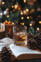 Glass of whiskey on an open book with pine cones and holiday gifts in the background photo