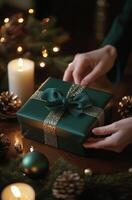 A person hands a beautifully wrapped green gift with gold ribbon in a cozy holiday setting photo