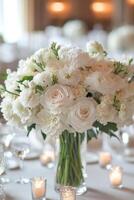 Elegant white flower arrangement in a decorative vase at a wedding reception table setting photo