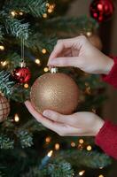 Decorating a Christmas tree with a handmade ornament in a cozy indoor setting during winter photo