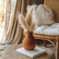 A cozy corner featuring a clay vase with pampas grass on a white book in a softly lit room photo