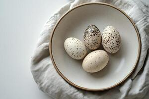 A collection of decorative eggs in a bowl on a soft fabric surface in natural light photo