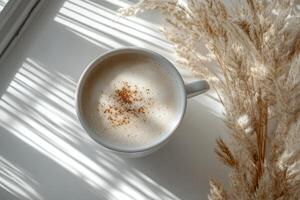 A cozy cup of cappuccino placed on a soft surface with dried grass in early morning light photo