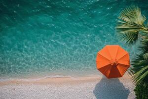Relaxing beach view with an orange umbrella near clear turquoise waters in a tropical paradise photo