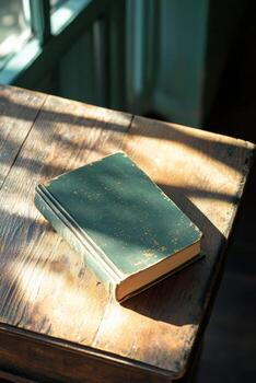 A leather bound book resting on a rustic wooden table near a sunny window with plants photo