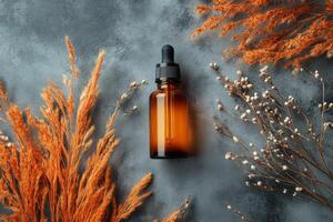 Brown glass dropper bottle on textured surface with decorative dried plants in autumn setting photo