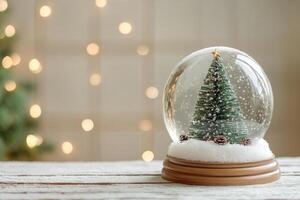 Decorative miniature Christmas tree and snow globe on wooden table with holiday lights in background photo