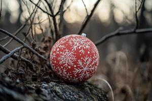 Red Christmas ornament decorated with silver snowflakes hangs on a snowy evergreen tree photo