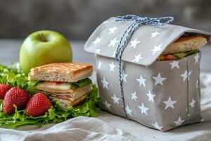 Freshly wrapped sandwich with strawberries and lettuce on a textured cloth in a bright kitchen photo