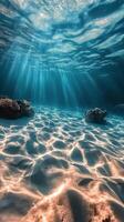 Underwater sunlight beams illuminating sandy ocean floor and coral formations during midday photo