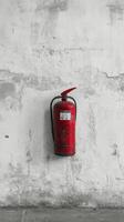 A red fire extinguisher mounted on a worn white wall in an industrial setting photo