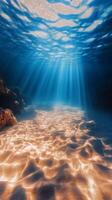 Underwater sunlight beams illuminating sandy ocean floor and coral formations during midday photo