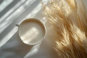 A cozy cup of cappuccino placed on a soft surface with dried grass in early morning light photo