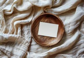 Blank White Card on Wooden Plate With Linen Fabric Background photo