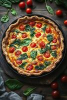 Fresh vegetable quiche with spinach and cherry tomatoes on a rustic wooden table photo
