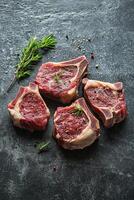 Fresh cut pork chops placed on a gray surface with a sprig of mint for garnish photo