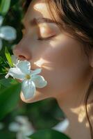 A young woman enjoys the fragrance of white flowers amidst lush greenery on a sunny day photo