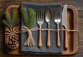 Elegant holiday dinner setting with cutlery, pinecones, and winter decorations on wooden table photo