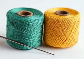 Spools of green and yellow thread with a sewing needle on a light background in a crafting workspace photo