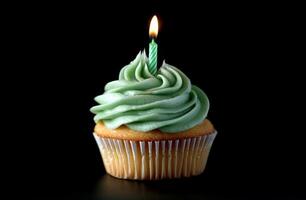 Delicious green frosted cupcake with a lit candle against a dark background photo