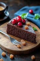 A delicious chocolate cake slice topped with cranberries and sugar crystals on a wooden board photo