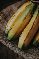 Bananas stacked on burlap fabric in a warm, rustic setting with natural lighting photo