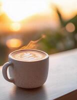 Coffee cup with latte art on a table during sunset at a cozy cafe photo