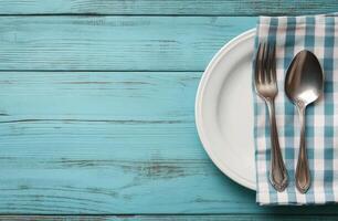 Rustic dining setup with vintage cutlery on a blue wooden table and checkered napkin photo