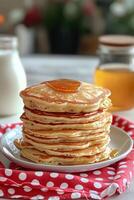 Stack of fluffy pancakes served with honey by a sunny window on a cozy autumn morning photo