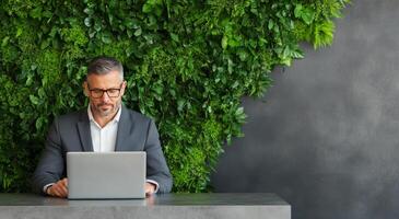 Professional man working on laptop in greenery filled office environment photo