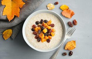Healthy breakfast bowl with oatmeal and mixed dried fruits on gray background photo