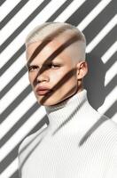 Young man with light hair poses in shadows and light from window blinds photo