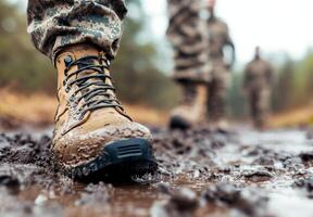 Soldiers in the rain preparing for training in a muddy environment with focus on combat boots photo