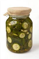 Homemade pickles preserved in a glass jar with herbs and spices photo