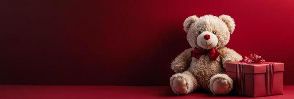 Soft bear beside a red gift box with a bow on a bright red background for festive occasions photo