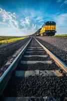 Train travels along railway tracks under a vibrant sky in rural area photo