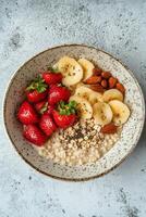 Breakfast bowl with oatmeal, berries, and nuts on a textured surface photo