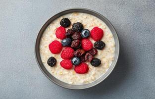 Healthy breakfast bowl with oatmeal and mixed dried fruits on gray background photo
