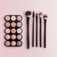 Makeup palette and brushes arranged on pink background for beauty and cosmetic enthusiasts photo