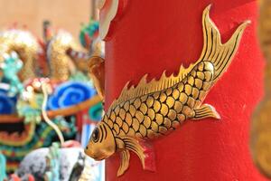 Cement carvings of fish are attached to the trunks of the pillars in the shrine. photo