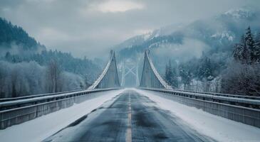 Suspension bridge covered in snow with misty mountains in the background during winter morning photo