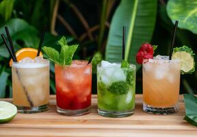 A selection of colorful refreshing cocktails served on a wooden table with lush greenery photo