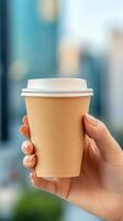 A person holds a brown disposable coffee cup outdoors in a city setting during the day photo