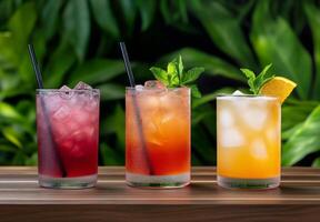A selection of colorful refreshing cocktails served on a wooden table with lush greenery photo